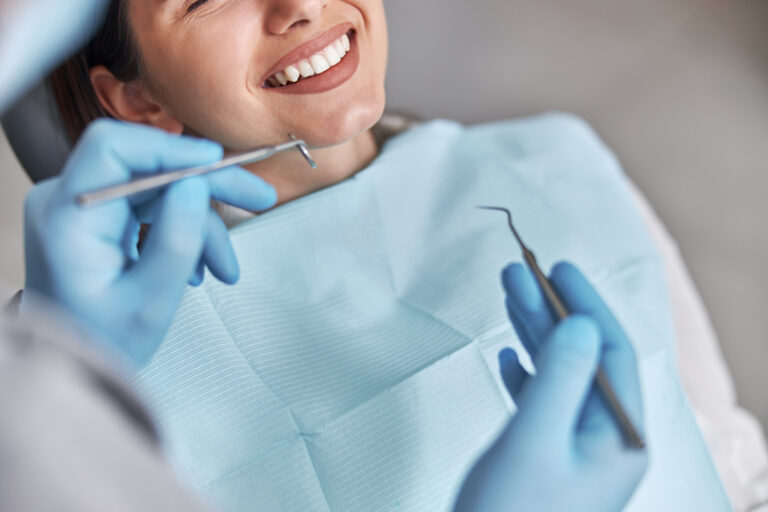 Cheerful positive dentist and client in dentistry. Female patient at dental procedure, doctor using dental instruments in modern dental clinic